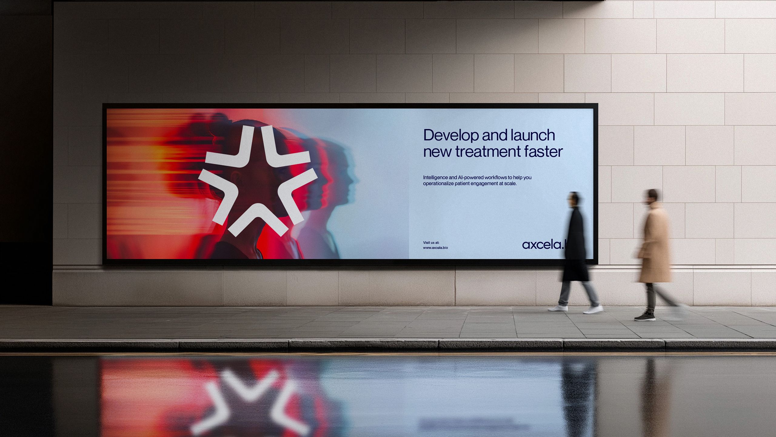 A large illuminated billboard in a station concourse carrying an Axcela Bio advert - a red-tinted, motion-streaked portrait beside the words “Develop and launch new treatment faster” - with two people walking past and the screen reflected in the wet floor
